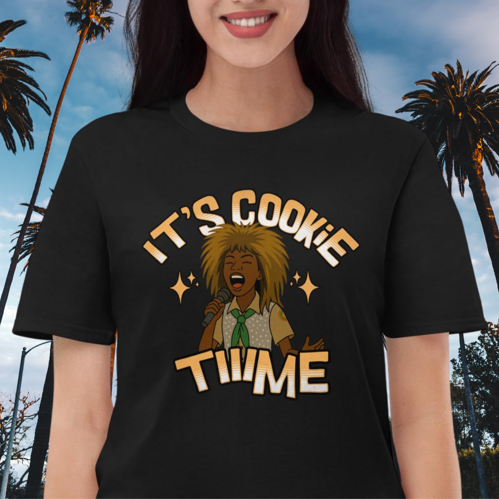 Black T-shirt featuring a cartoon-style illustration of a woman in a scout uniform with big 80s hair singing into a microphone, with the phrase “It’s Cookie Time” in bold retro letters, inspired by Troop Beverly Hills.
